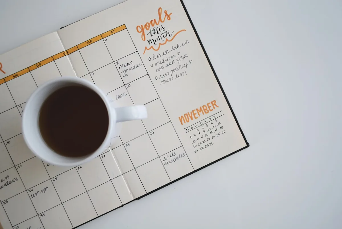 Taza de café sobre una agenda mensual, recordatorio para agendar tu control de salud